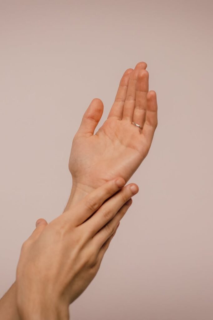 Close-up of hands gently caressing each other, symbolizing self-care and softness.